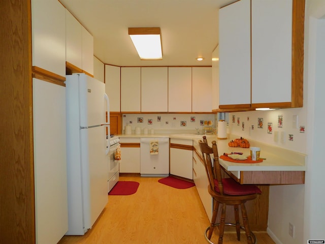 kitchen featuring white cabinets, backsplash, a breakfast bar, light hardwood / wood-style flooring, and white appliances