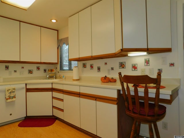 kitchen with white dishwasher, white cabinetry, and light hardwood / wood-style flooring