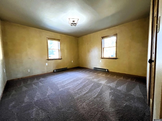 empty room featuring a baseboard heating unit, dark carpet, and plenty of natural light