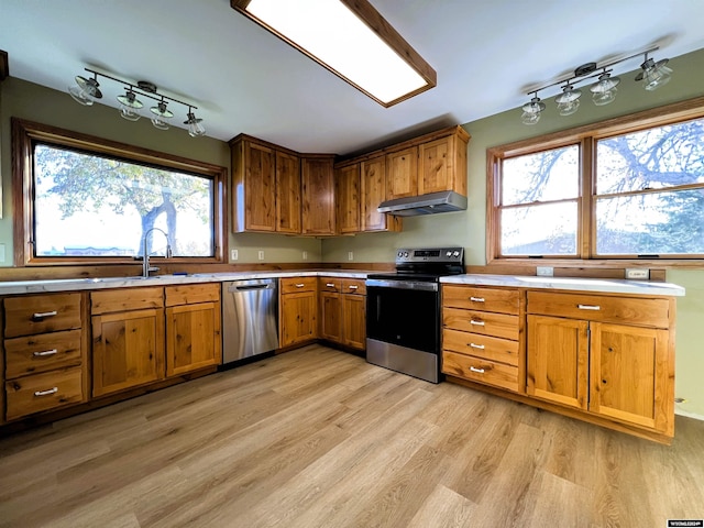 kitchen with stainless steel appliances, a healthy amount of sunlight, sink, and light hardwood / wood-style flooring