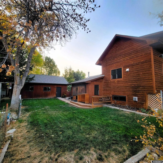 back house at dusk featuring a lawn