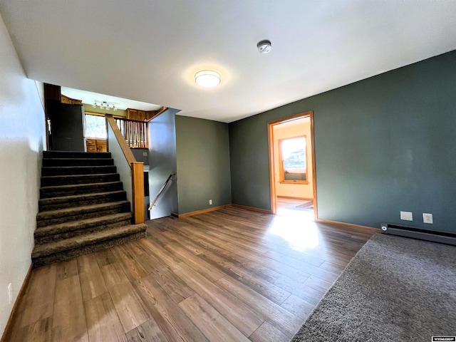 empty room featuring wood-type flooring, plenty of natural light, and a baseboard radiator