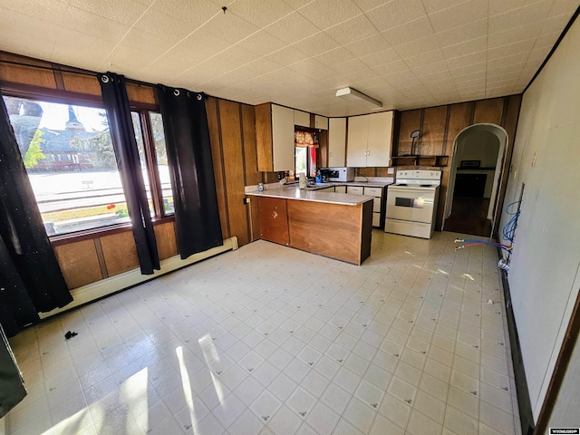 kitchen featuring wood walls, white appliances, kitchen peninsula, and a baseboard heating unit