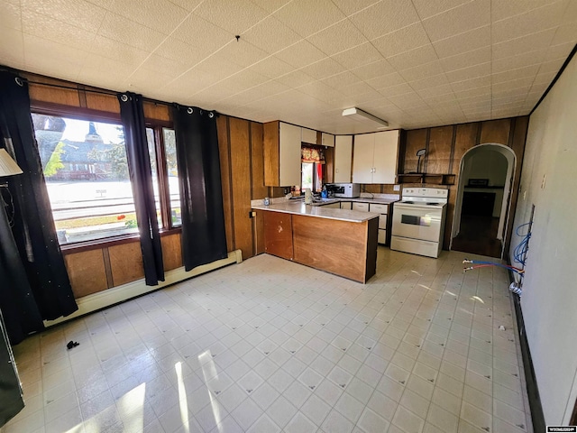 kitchen with wood walls, white appliances, kitchen peninsula, and a baseboard radiator