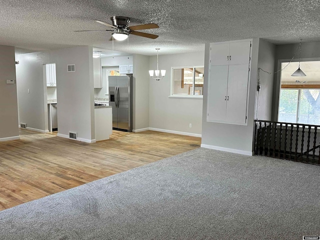 unfurnished living room featuring a healthy amount of sunlight, light wood-type flooring, and a textured ceiling