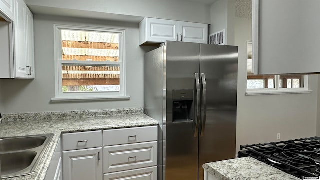 kitchen featuring white cabinetry, sink, and stainless steel fridge