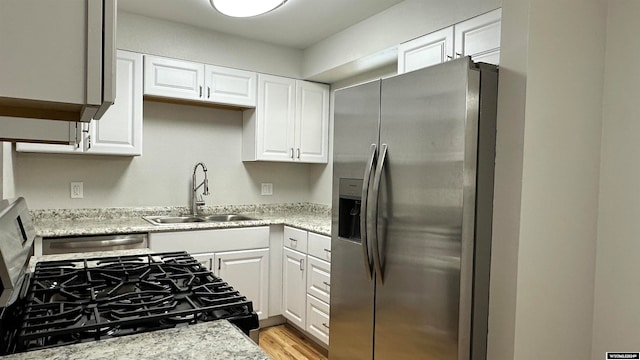 kitchen featuring white cabinets, appliances with stainless steel finishes, sink, and light hardwood / wood-style flooring