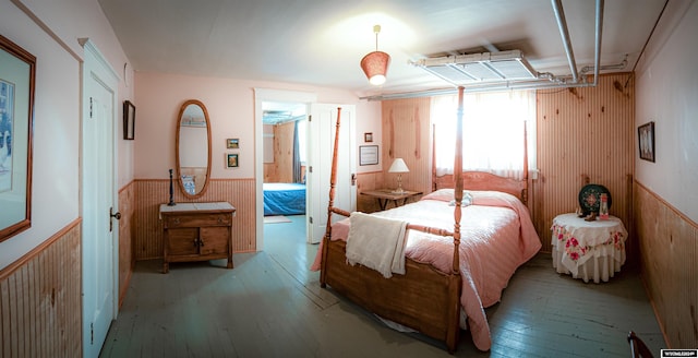 bedroom featuring wood walls, light hardwood / wood-style floors, and connected bathroom