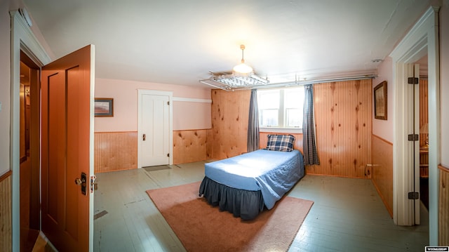 bedroom featuring wooden walls and light hardwood / wood-style flooring