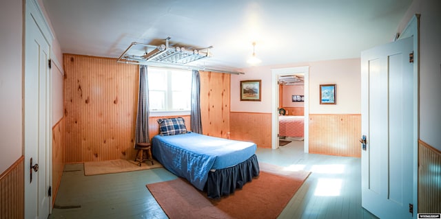 bedroom with light hardwood / wood-style flooring and wooden walls