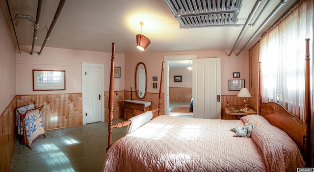 bedroom featuring wood walls, multiple windows, and hardwood / wood-style flooring