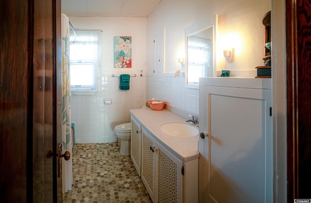 bathroom with toilet, vanity, tile walls, and tile patterned flooring