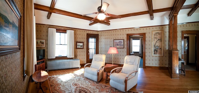 sitting room with hardwood / wood-style floors, radiator, and beamed ceiling