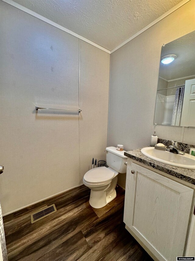 bathroom with hardwood / wood-style flooring, ornamental molding, a shower with shower curtain, vanity, and toilet