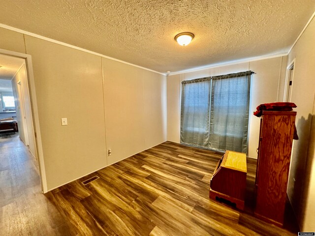 unfurnished room featuring hardwood / wood-style floors, a textured ceiling, and crown molding