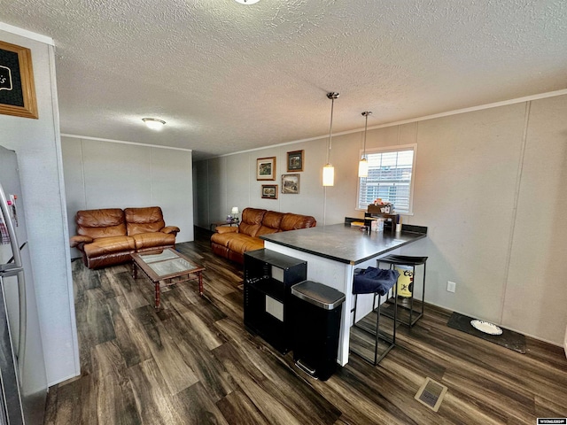 kitchen featuring dark hardwood / wood-style floors, a textured ceiling, decorative light fixtures, and kitchen peninsula