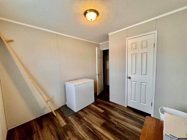 bedroom featuring refrigerator, dark hardwood / wood-style floors, a textured ceiling, and crown molding