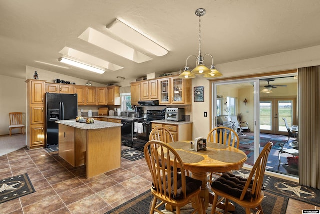 kitchen featuring black appliances, vaulted ceiling with skylight, ceiling fan, ventilation hood, and a kitchen island