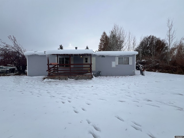 snow covered back of property featuring a deck