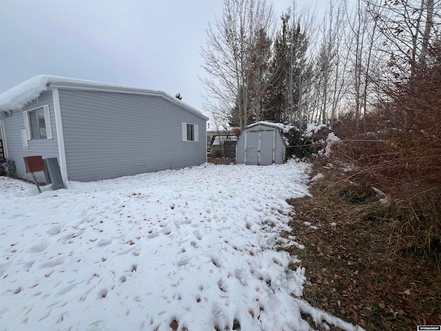 snowy yard featuring a shed