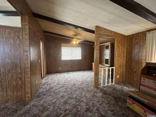 interior space featuring wood walls, ceiling fan, and lofted ceiling with beams