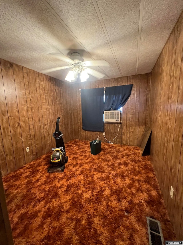 unfurnished bedroom featuring carpet flooring, a textured ceiling, wooden walls, and ceiling fan