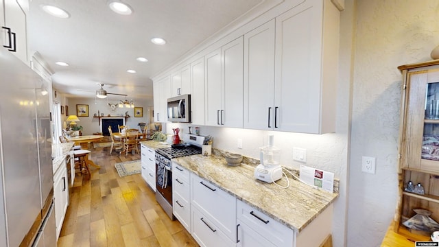 kitchen featuring white cabinetry, stainless steel appliances, ceiling fan, and light hardwood / wood-style flooring