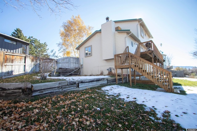 snow covered rear of property with a wooden deck