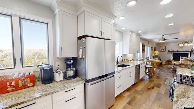 kitchen with stainless steel appliances, white cabinets, sink, and light hardwood / wood-style flooring