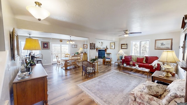 living room with hardwood / wood-style floors, ceiling fan with notable chandelier, and a healthy amount of sunlight