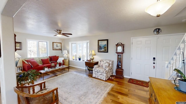 living room with light hardwood / wood-style flooring, a textured ceiling, and ceiling fan