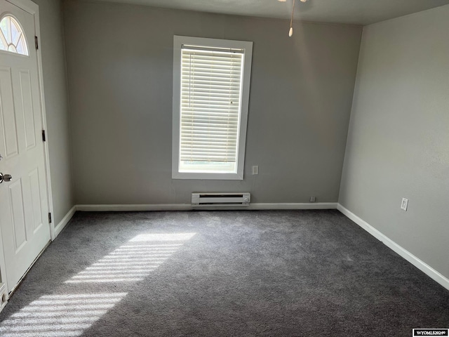 spare room featuring baseboard heating, dark colored carpet, and ceiling fan