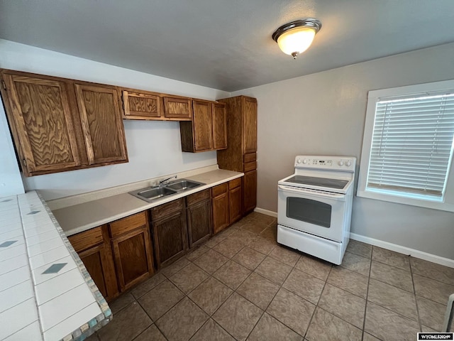 kitchen featuring sink, tile counters, light tile patterned flooring, and electric range