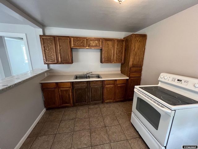 kitchen with dark tile patterned floors, sink, and white electric range oven