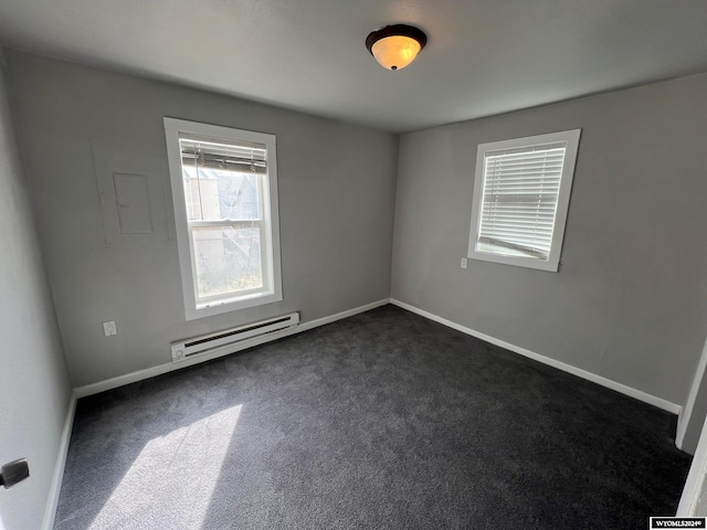 spare room with dark colored carpet and a baseboard radiator