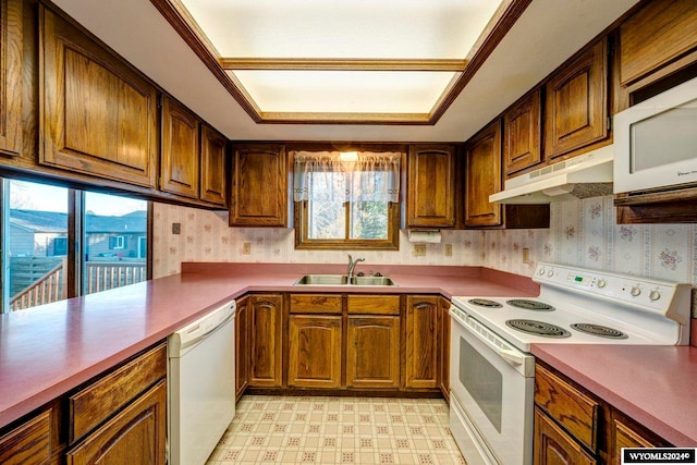 kitchen with white appliances, plenty of natural light, sink, and kitchen peninsula