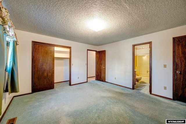 unfurnished bedroom with ensuite bath, light colored carpet, and a textured ceiling