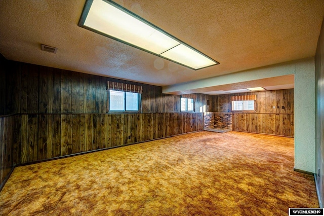 spare room with wood walls, a textured ceiling, and carpet floors