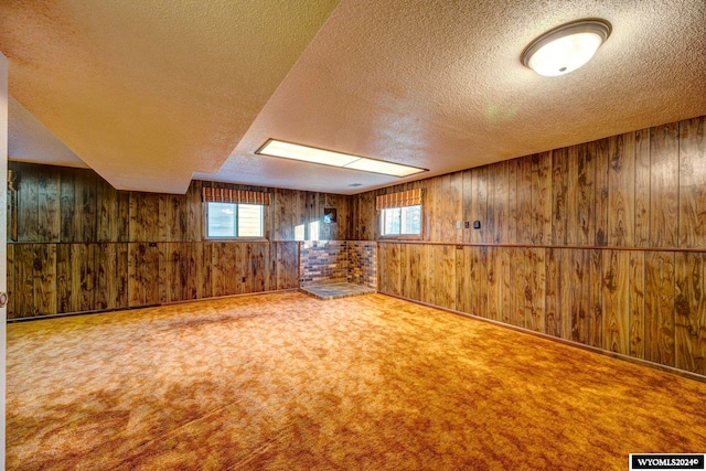 interior space with carpet flooring, wooden walls, and a textured ceiling