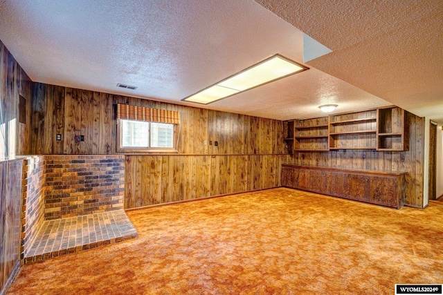 basement featuring wood walls, a textured ceiling, and light carpet