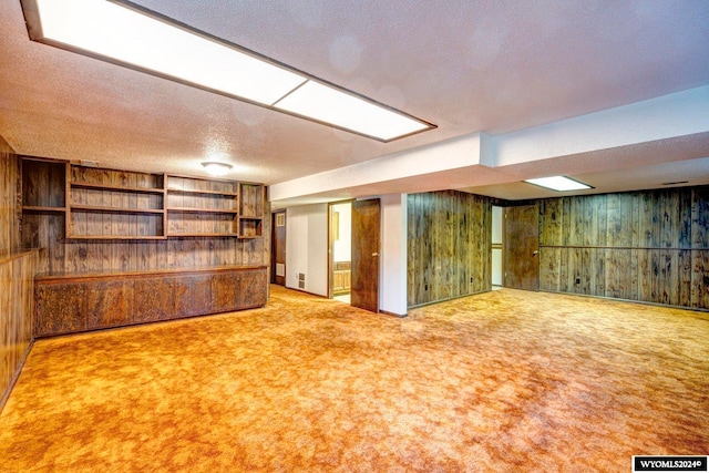 basement featuring wood walls, carpet, and a textured ceiling