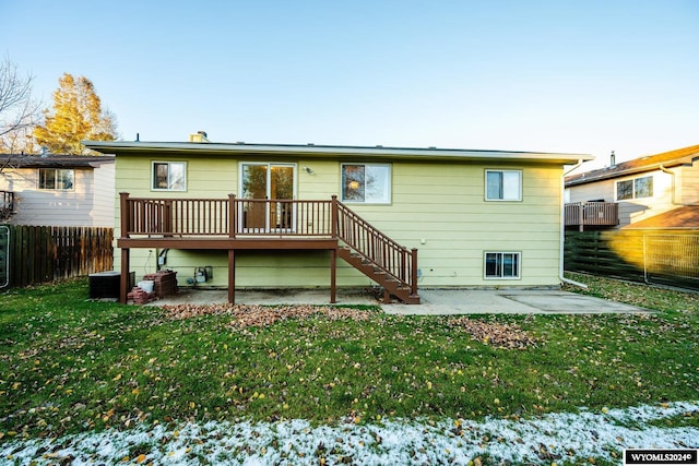 snow covered property featuring a lawn, a wooden deck, and a patio