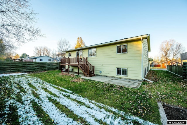 snow covered back of property featuring a patio area, a yard, and a wooden deck