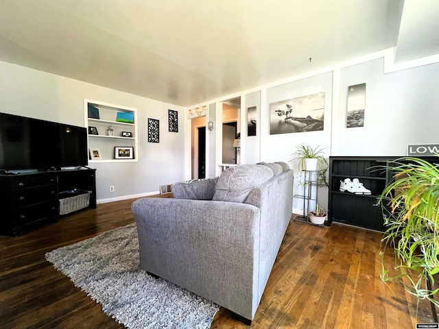 living room featuring dark hardwood / wood-style flooring and built in shelves