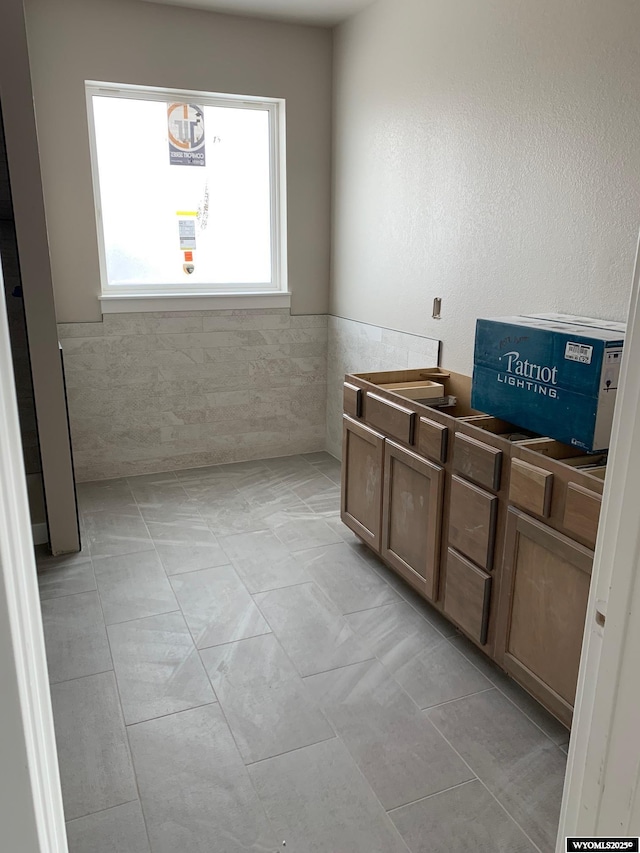 bathroom featuring wainscoting and tile walls