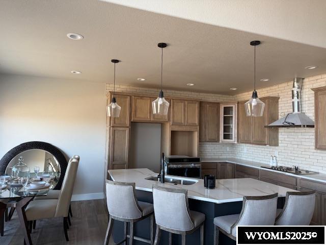 3698 Red Wolf Dr, Casper, WY 82604 - kitchen with a sink, wood finished floors, a kitchen island with sink, appliances with stainless steel finishes, and light stone countertops