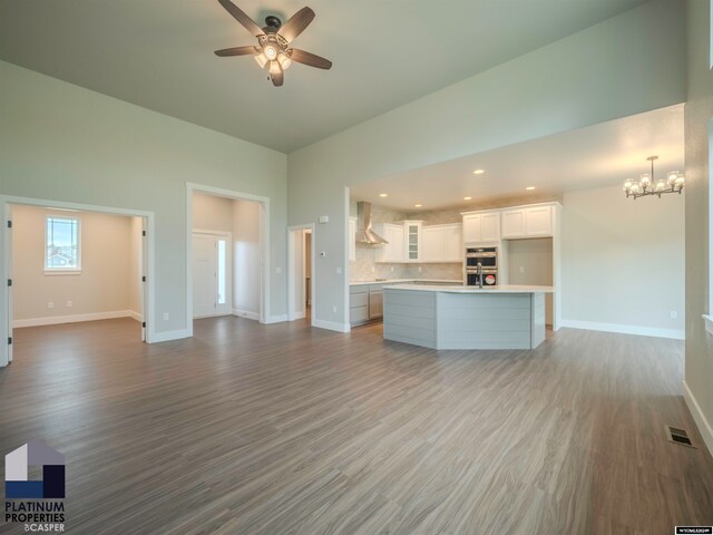 unfurnished living room featuring recessed lighting, visible vents, wood finished floors, baseboards, and ceiling fan with notable chandelier