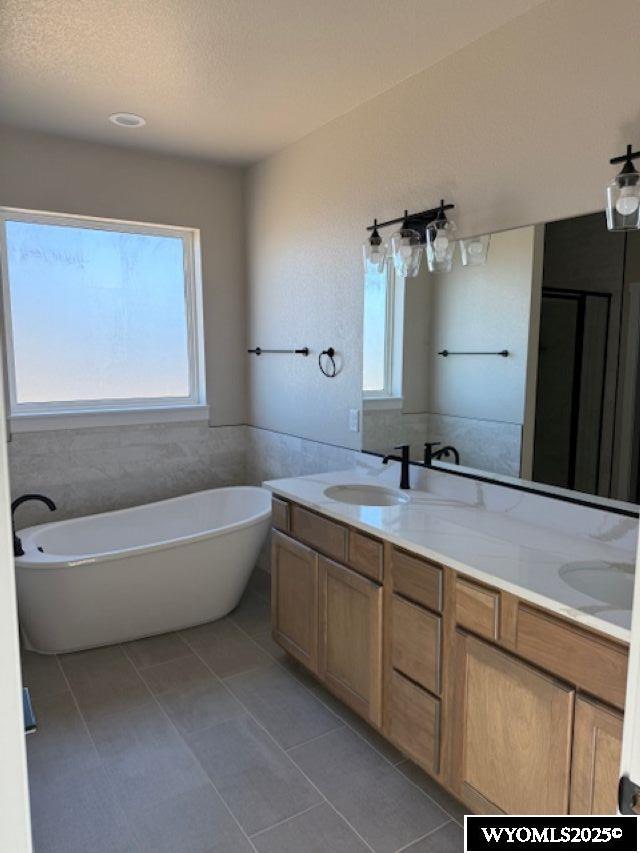 3698 Red Wolf Dr, Casper, WY 82604 - bathroom with double vanity, a freestanding tub, and tile patterned floors