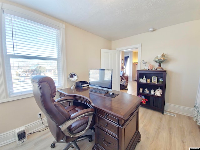 home office featuring light wood-type flooring and a healthy amount of sunlight