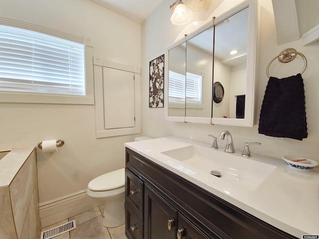 bathroom with toilet, vanity, and tile patterned floors